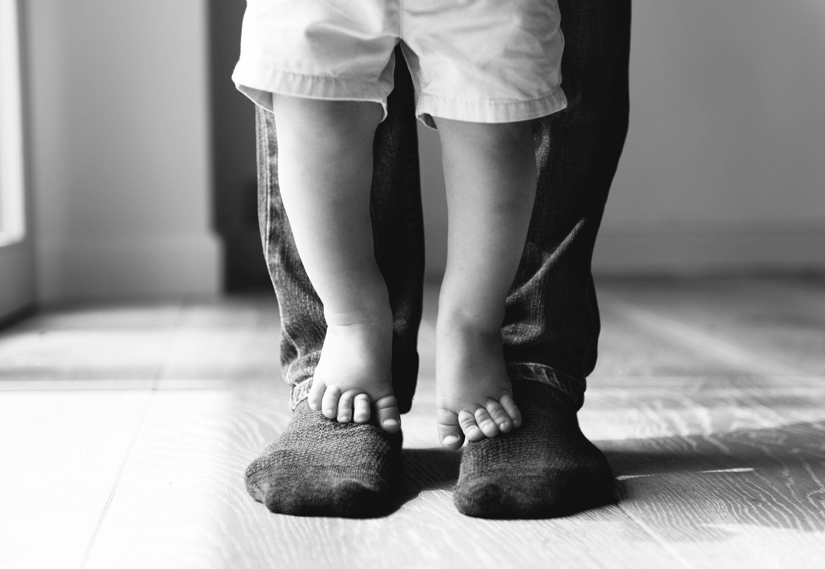Baby steht auf anderen Papas Füßen